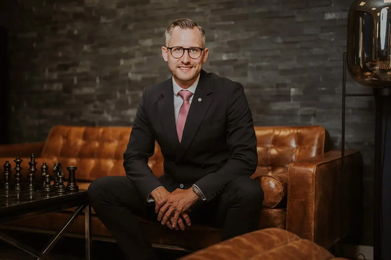 Businessportrait von Jasper Verbeek in einem dunklen Anzug auf einem Ledersofa